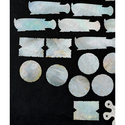 104 - A collection of Chinese carved mother of pearl gaming tokens including some in the form of fish, the... 