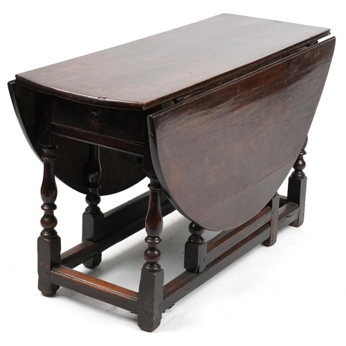 1022 - An 18th century oval gateleg table raised on turned and block supports, 70cm high x 120cm wide