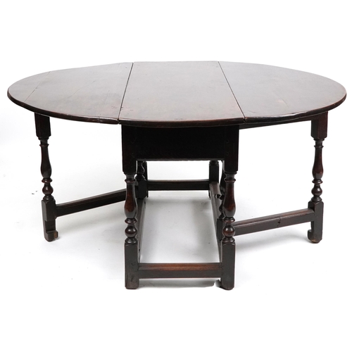 1022 - An 18th century oval gateleg table raised on turned and block supports, 70cm high x 120cm wide