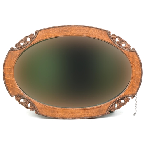 1069 - An Edwardian oak oval wall mirror, 52cm x 77cm.