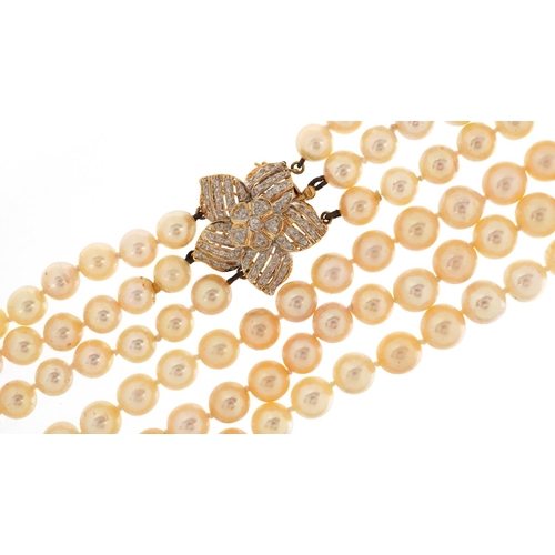 63 - A cultured pearl three row necklace with 18ct gold diamond set flower head clasp, each pearl approxi... 