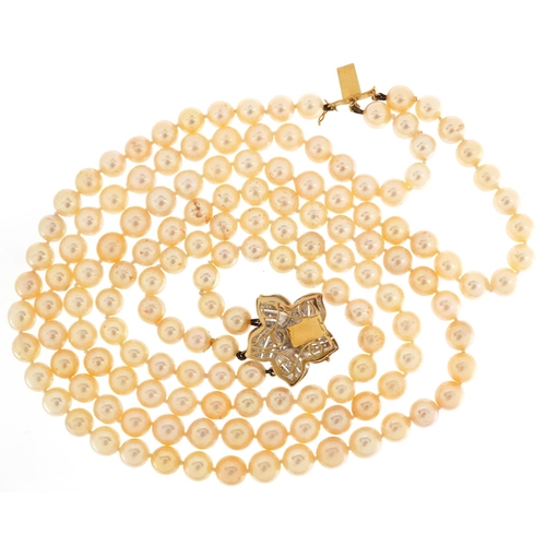 63 - A cultured pearl three row necklace with 18ct gold diamond set flower head clasp, each pearl approxi... 