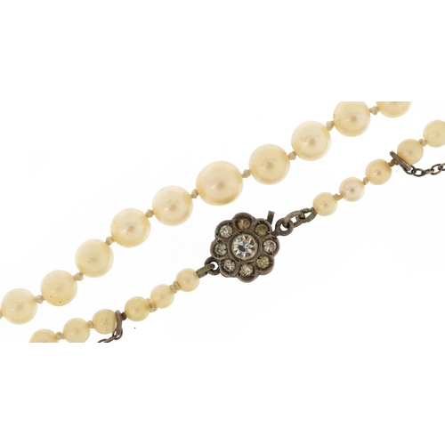 2200 - A graduated single string pearl necklace with silver clasp set with clear stones, the largest pearl ... 