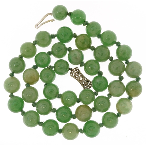 A Chinese green jade bead necklace with unmarked white gold clasp set with diamonds, each bead 9.5mm in diameter, overall 47cm in length, 57.0g.