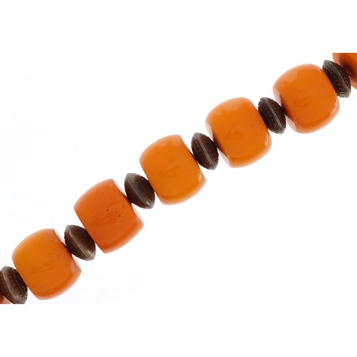 628 - An amber coloured bead necklace with white metal spacers and clasp, each bead approximately 21mm in ... 