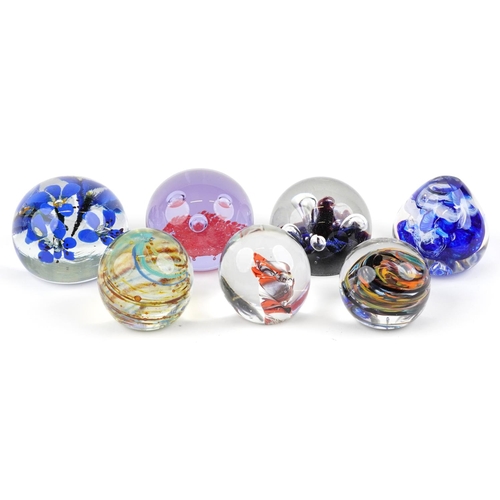 435 - A group of seven late 20th century glass paperweights, variously sized, the largest 10cm in diameter... 