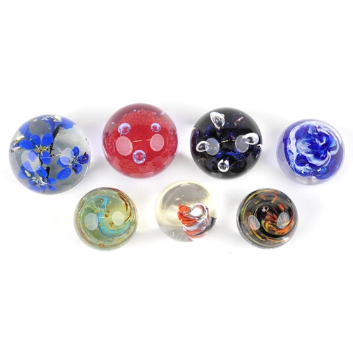 435 - A group of seven late 20th century glass paperweights, variously sized, the largest 10cm in diameter... 