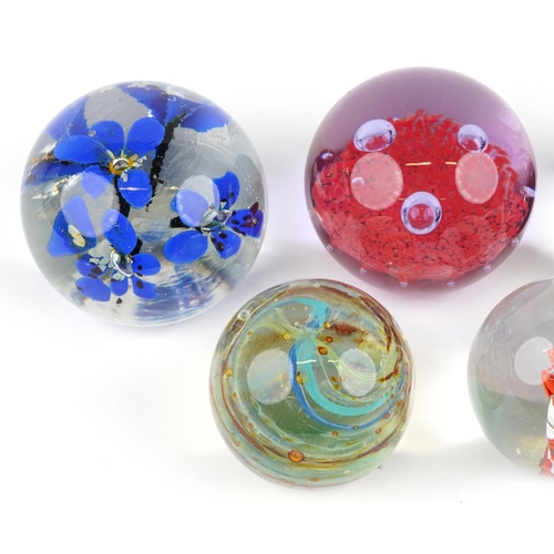 435 - A group of seven late 20th century glass paperweights, variously sized, the largest 10cm in diameter... 