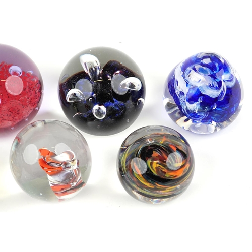 435 - A group of seven late 20th century glass paperweights, variously sized, the largest 10cm in diameter... 