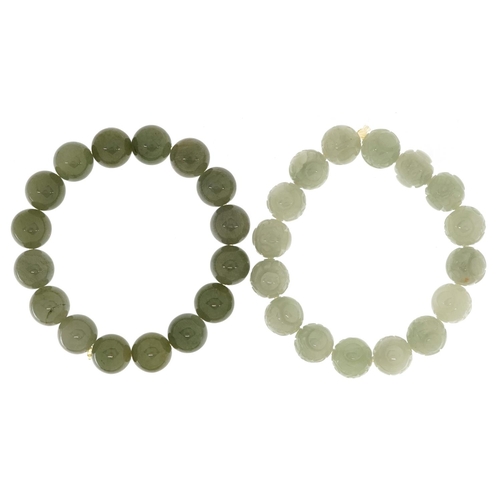 53 - Two Chinese jade bead bangles, one with carved decoration, the other spinach green.