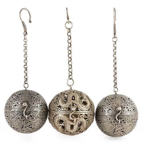 64 - Three Chinese white metal gimbal incense burners, the largest 5.5cm in diameter.