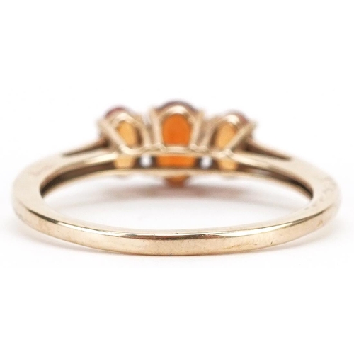 2348 - A 9ct gold orange garnet three stone ring, size N, 1.9g.