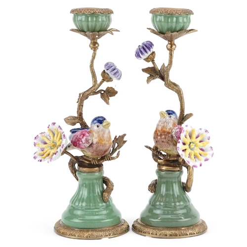 1192 - A pair of continental porcelain candlesticks decorated with a bird beside a flower.