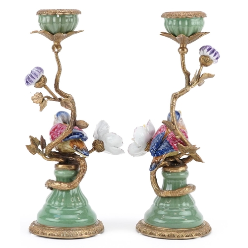 1192 - A pair of continental porcelain candlesticks decorated with a bird beside a flower.