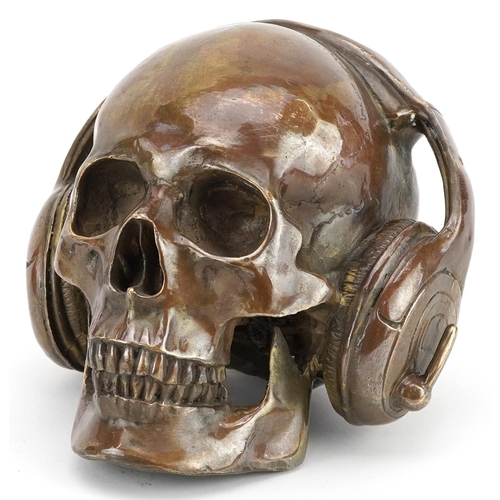 1187 - A Steam Punk interest patinated bronze model of a human skull wearing headphones, 16.5cm high.