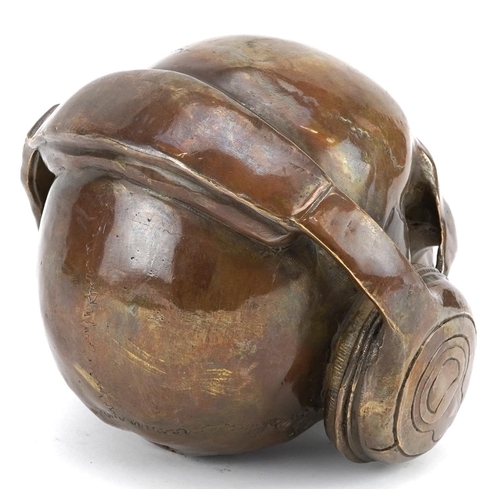 1187 - A Steam Punk interest patinated bronze model of a human skull wearing headphones, 16.5cm high.