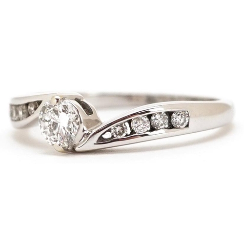 445 - An 18ct white gold diamond solitaire crossover ring with diamond set shoulders, total diamond weight... 