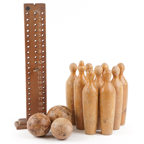 579 - A mid 20th century skittles game including nine pins, three balls and a score board, the pins 31cm h... 