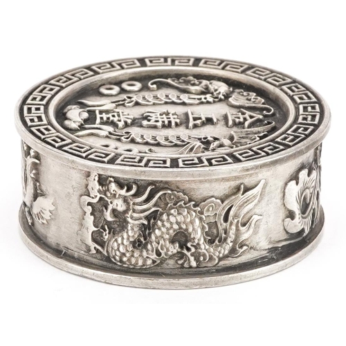 1165 - A Chinese white metal circular box and cover decorated with dragons and bats, 5cm in diameter, 106.2... 