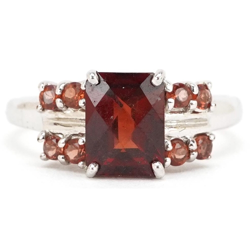 2288 - A 9ct white gold rectangular cut garnet ring with garnet set shoulders, size N, 2.8g.