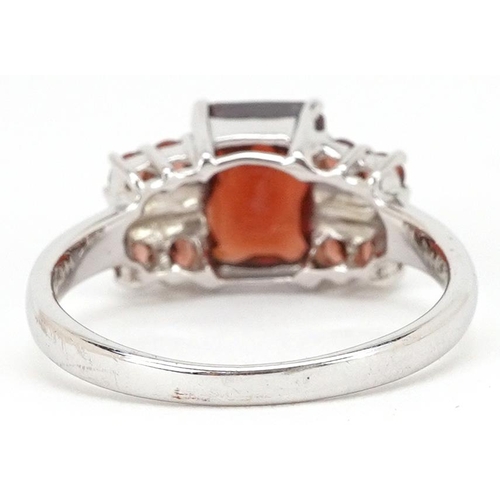 2288 - A 9ct white gold rectangular cut garnet ring with garnet set shoulders, size N, 2.8g.