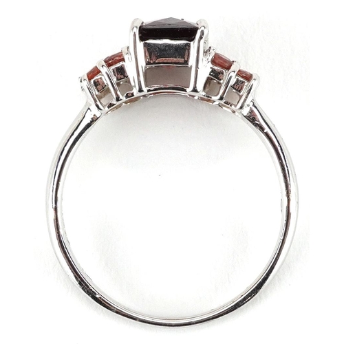 2288 - A 9ct white gold rectangular cut garnet ring with garnet set shoulders, size N, 2.8g.