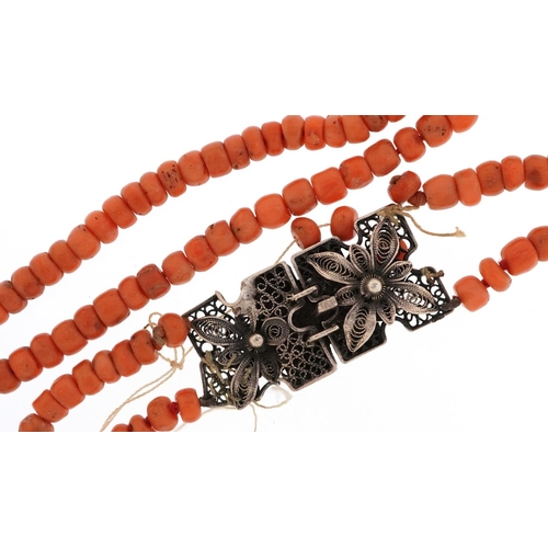 2500 - An Antique pink coral two row necklace with unmarked filigree silver clasp, 40cm in length, 40.2g.