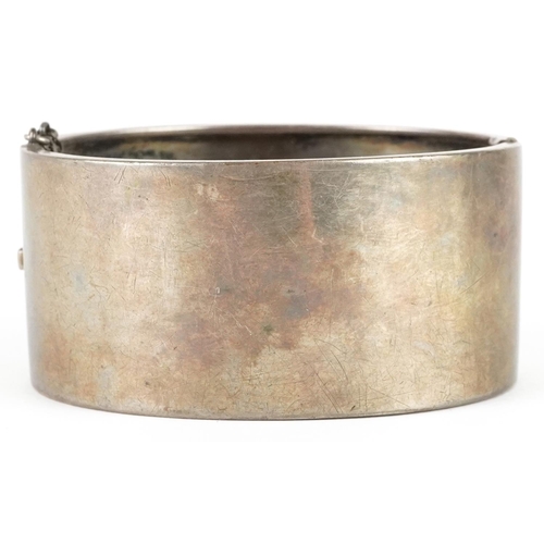 2338 - A large Victorian unmarked silver aesthetic hinged bangle, 6.5cm wide x 3cm high, 43.0g.