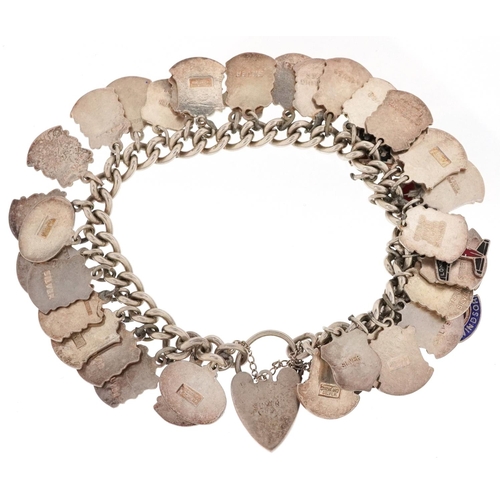 2065 - A silver charm bracelet with a large collection of silver and enamel souvenir shield charms, 80.8g.