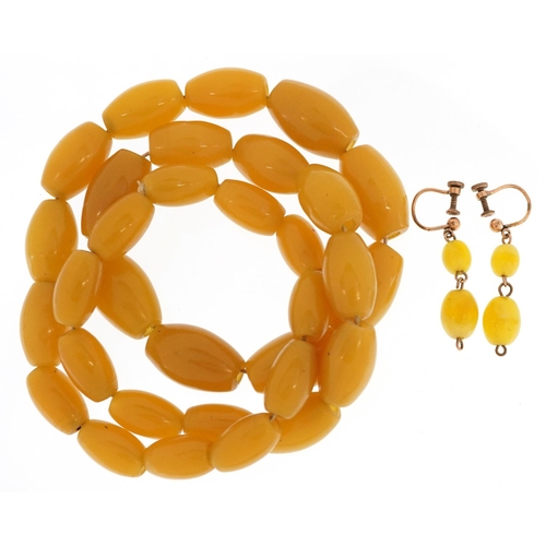 2537 - An amber coloured bead necklace and a pair of similar earrings with yellow metal mounts, the necklac... 