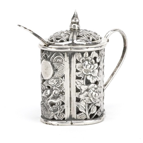 61 - A Chinese export silver mustard with spoon and clear glass liner, pierced and embossed with a dragon... 