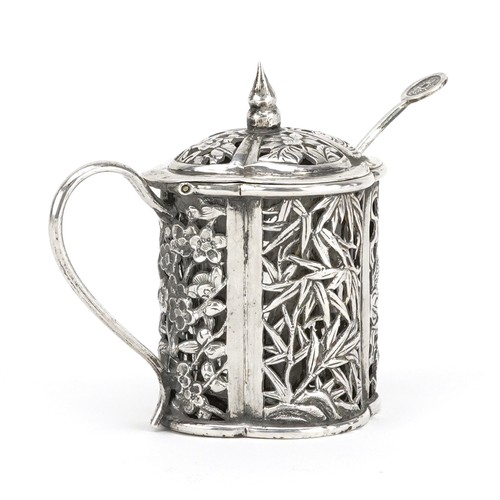 61 - A Chinese export silver mustard with spoon and clear glass liner, pierced and embossed with a dragon... 