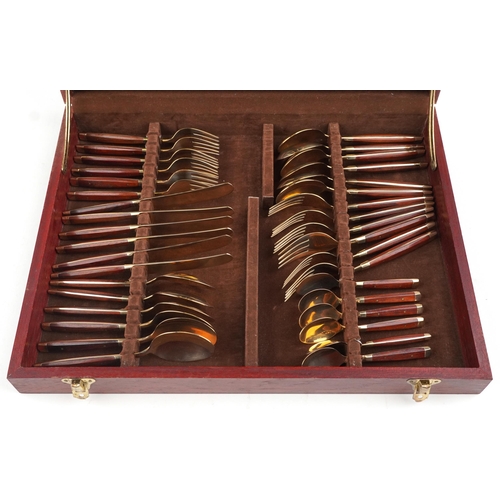 591 - A six place mahogany canteen of bronze cutlery with wooden handles, the canteen 42.5cm wide.