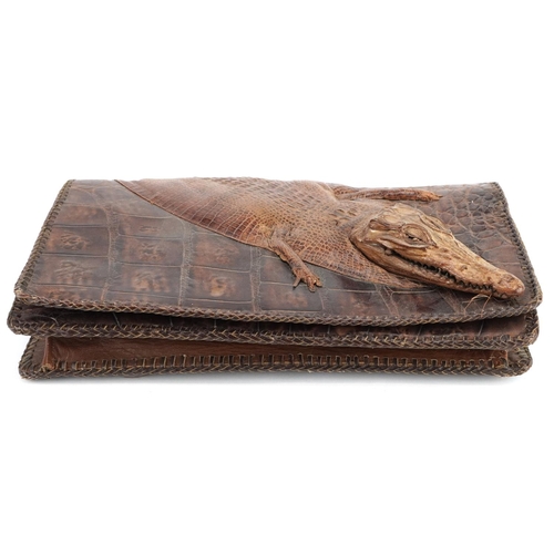 291 - An early 20th century crocodile skin clutch bag, 31cm wide, together with another clutch bag.