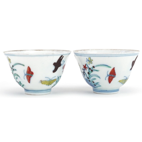 342 - A pair of Chinese porcelain tea bowls hand painted with flowers and insects, six figure character ma... 