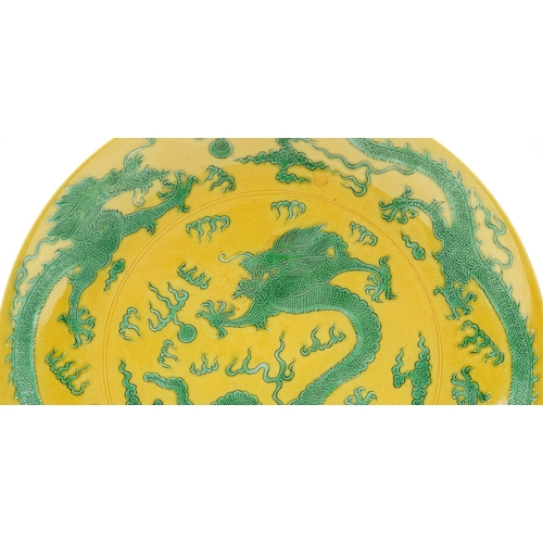 80 - A Chinese porcelain charger hand painted with dragons chasing the flaming pearl, onto a yellow groun... 