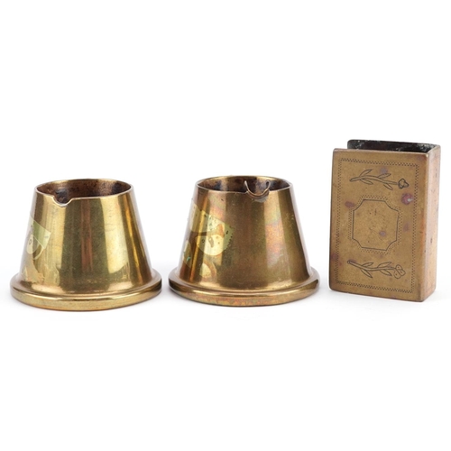 2468 - A pair of trench art brass shell case ashtrays and a matchbox holder.