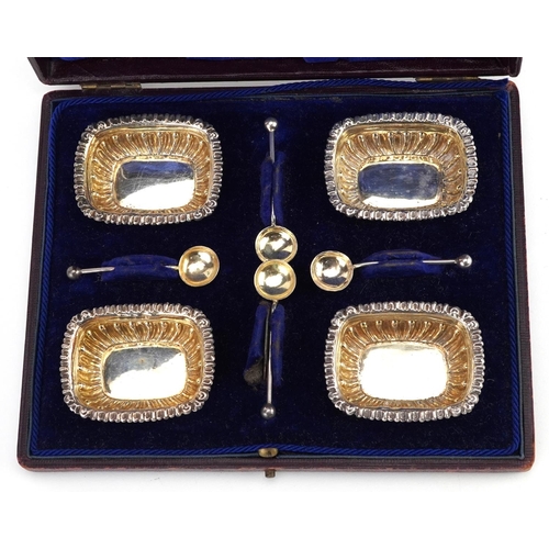 541 - William Devenport, a set of four Edwardian silver open salts with spoons housed in a velvet and silk... 