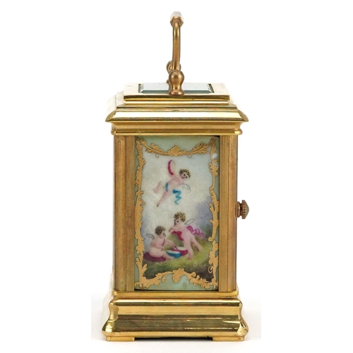 94 - A miniature brass cased carriage clock with swing handle and Sèvres style panels hand painted with P... 