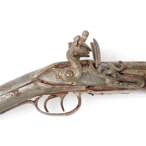 2555 - An antique Middle Eastern double barrel flintlock rifle, the wooden stock carved carved with a figur... 