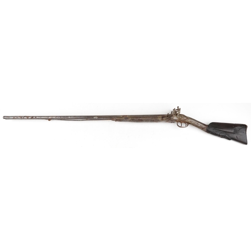 2555 - An antique Middle Eastern double barrel flintlock rifle, the wooden stock carved carved with a figur... 