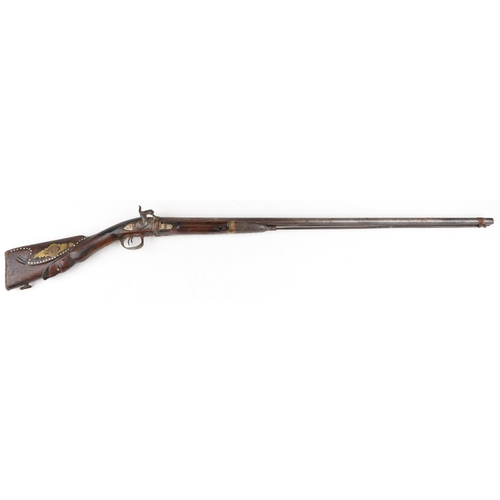 2554 - An antique Middle Eastern double barrel flintlock rifle, the wooden stock carved with a serpent head... 