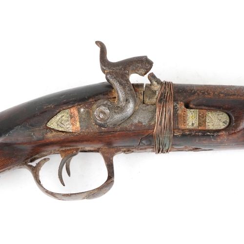 2554 - An antique Middle Eastern double barrel flintlock rifle, the wooden stock carved with a serpent head... 