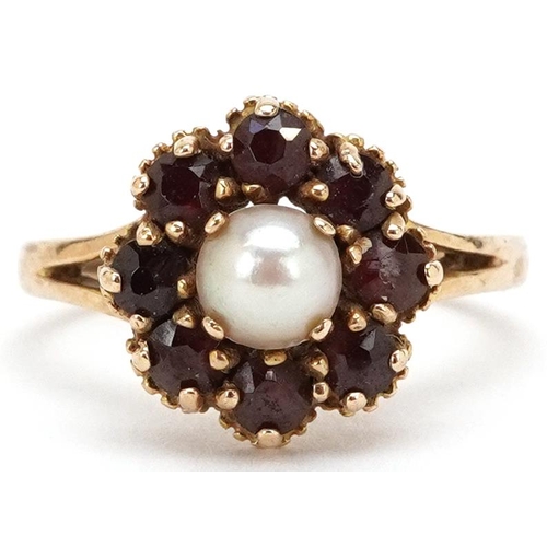 3341 - A 9ct gold cultured pearl and garnet flower head ring with split shoulders, size O, 3.6g.