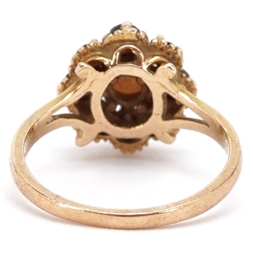 3341 - A 9ct gold cultured pearl and garnet flower head ring with split shoulders, size O, 3.6g.