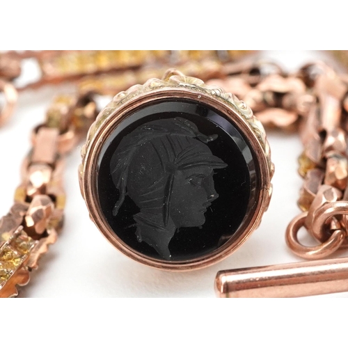  A Victorian 9ct rose gold watch chain with T bar and black onyx intaglio seal fob carved with a Roma... 