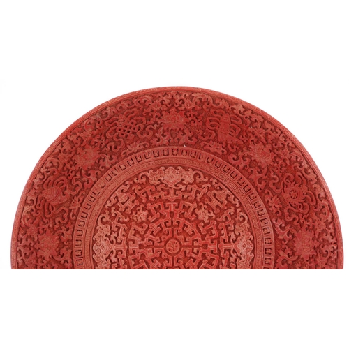 398 - A Chinese cinnabar lacquered circular plate, 20th century, profusely decorated in relief, 29cm in di... 