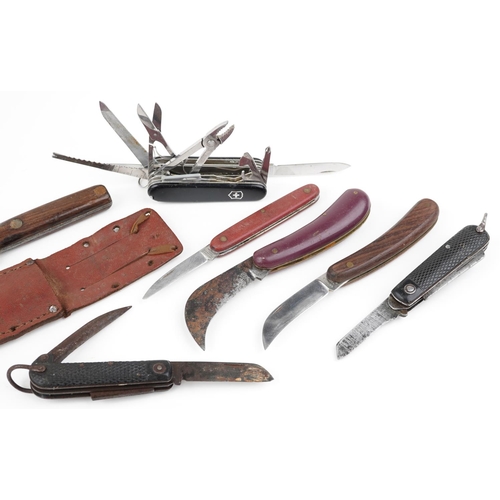 2498 - A group of six folding penknives together with an early 20th wooden handled knife in a leather sheat... 