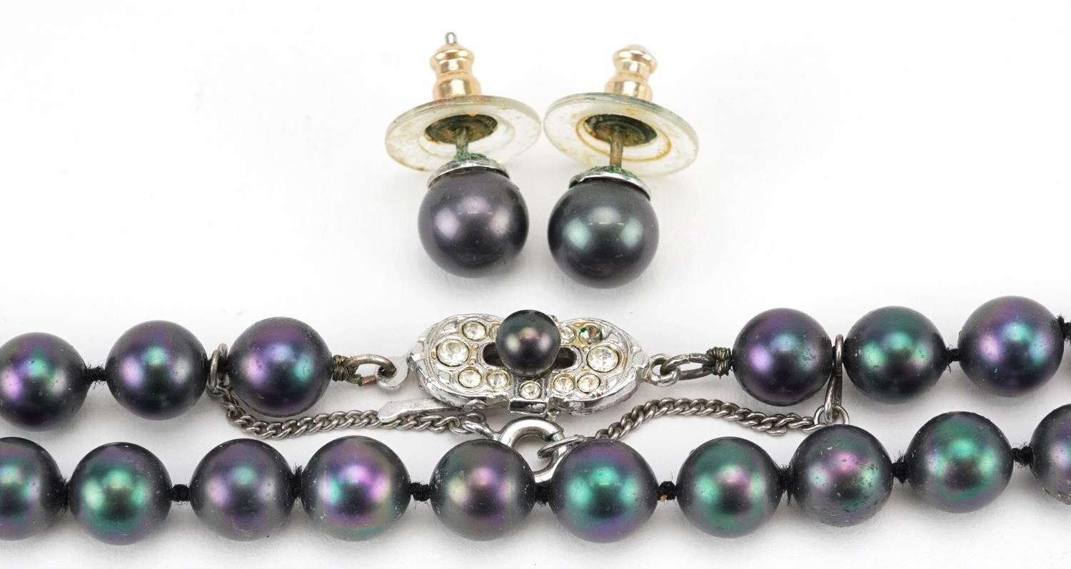 A single string black pearl necklace with silver clasp and a