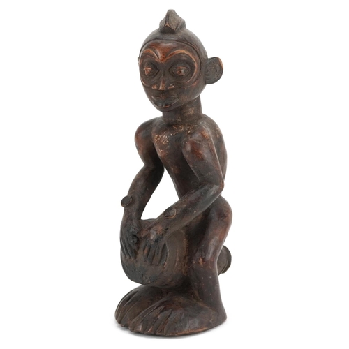 200 - An African figure of a drummer, late 19th/early 20th century, the head shaved with a coxcomb, a cyli... 